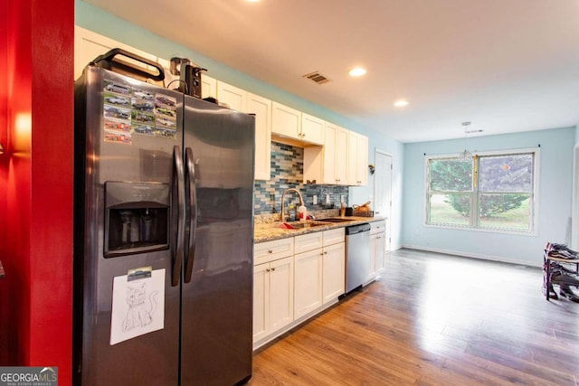 kitchen featuring decorative backsplash, white cabinets, appliances with stainless steel finishes, light wood-type flooring, and pendant lighting