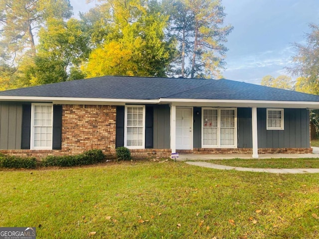 single story home featuring roof with shingles, brick siding, board and batten siding, and a front yard