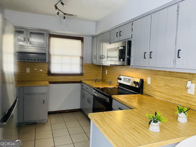 kitchen featuring light tile patterned floors, gray cabinets, stainless steel appliances, and light countertops