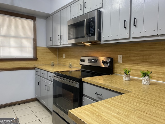 kitchen with stainless steel appliances, gray cabinetry, decorative backsplash, and light tile patterned floors