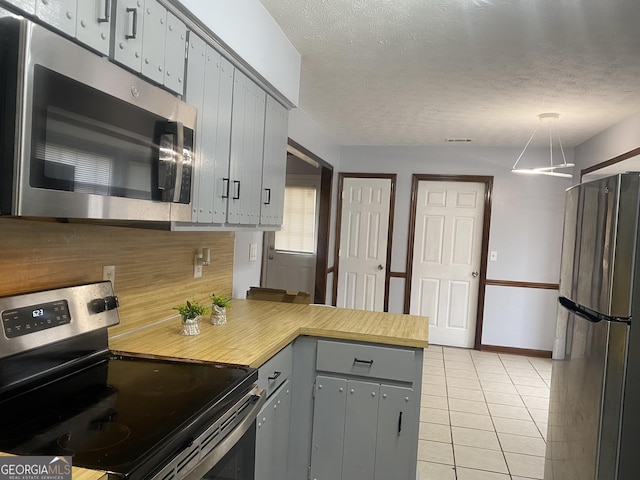 kitchen with light tile patterned floors, stainless steel appliances, a textured ceiling, and gray cabinets