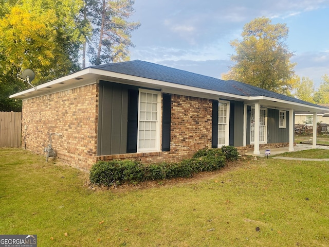 view of front of house featuring board and batten siding, a front yard, and brick siding