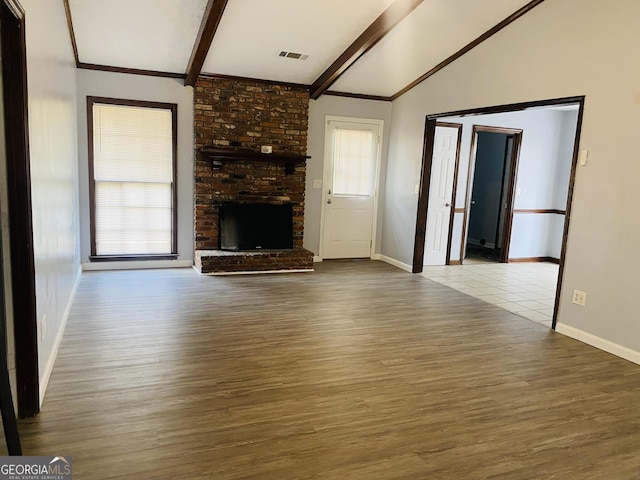 unfurnished living room with baseboards, visible vents, lofted ceiling with beams, wood finished floors, and a fireplace