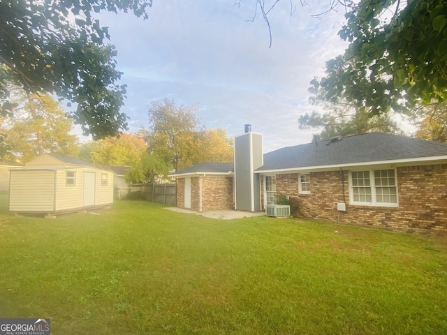 rear view of house featuring brick siding, a yard, fence, a shed, and an outdoor structure