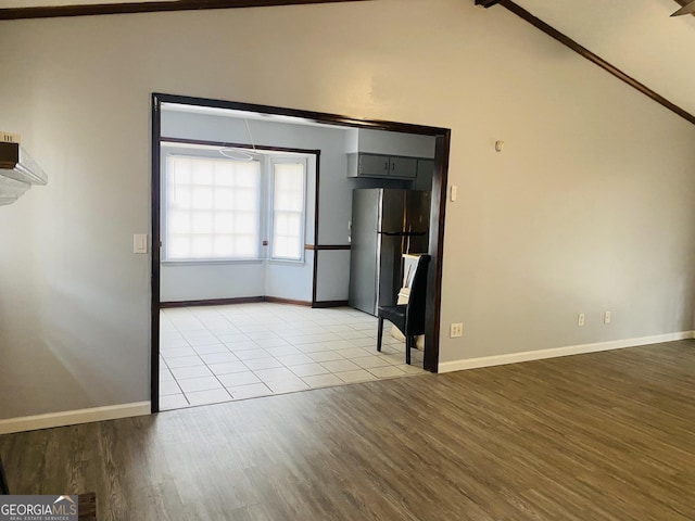 unfurnished room featuring lofted ceiling, baseboards, and light wood-style floors