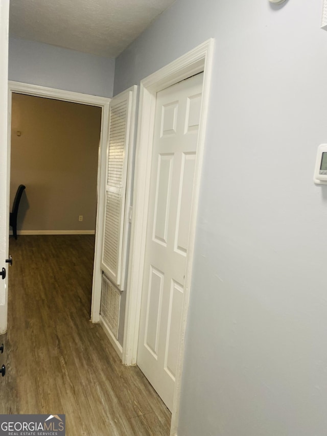 hall featuring wood finished floors, visible vents, and baseboards