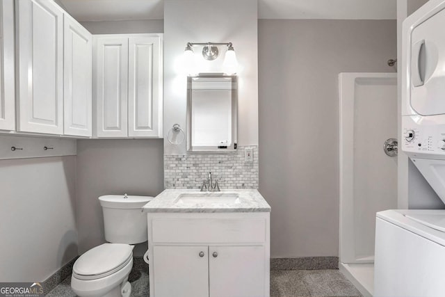 bathroom with backsplash, vanity, stacked washer / drying machine, a shower, and toilet