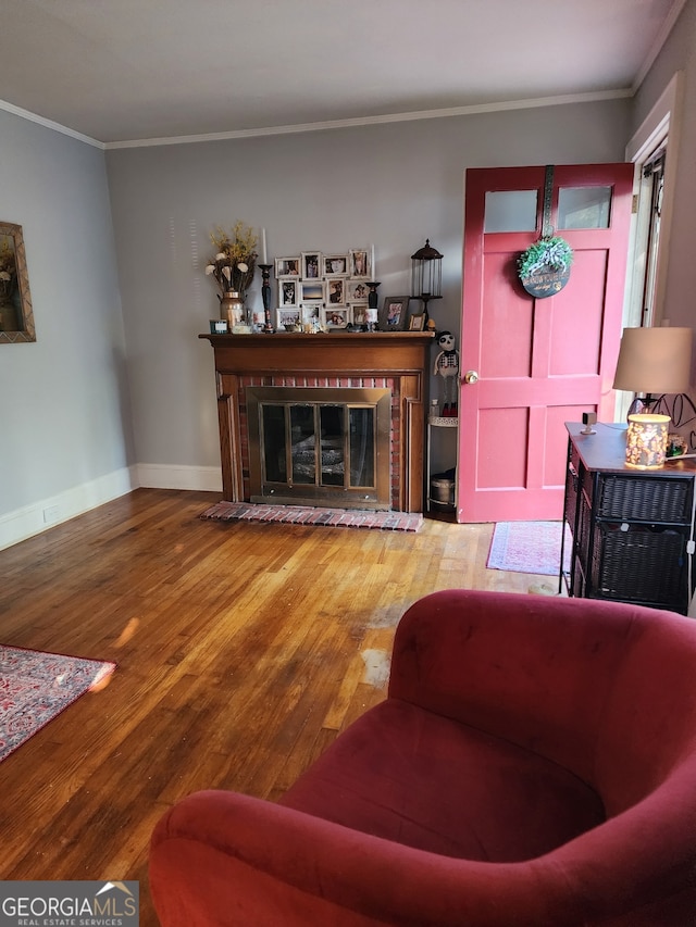 living room featuring ornamental molding, hardwood / wood-style floors, and a brick fireplace