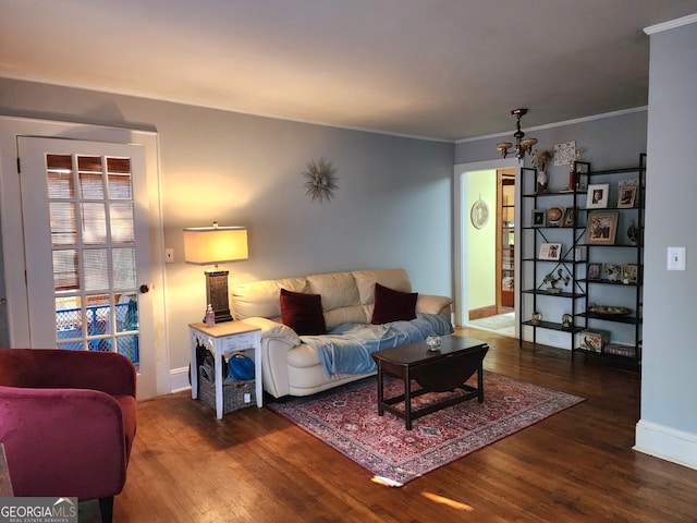 living room with crown molding, a chandelier, and dark hardwood / wood-style flooring