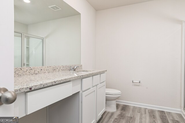 bathroom featuring vanity, toilet, hardwood / wood-style flooring, and a shower with door