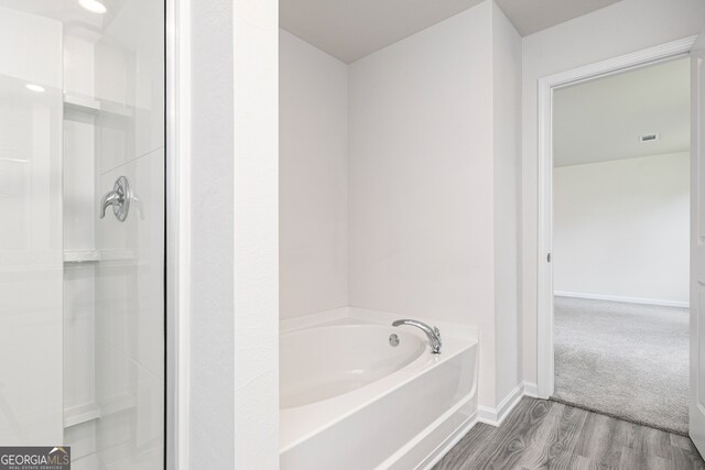 bathroom with shower with separate bathtub and wood-type flooring