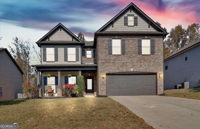 front of property with central air condition unit, a lawn, a porch, and a garage