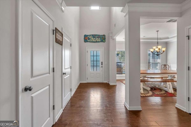 entrance foyer featuring ornamental molding, dark wood-type flooring, and a notable chandelier