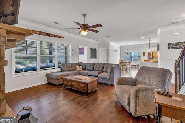 living room featuring ornamental molding, dark hardwood / wood-style floors, and ceiling fan with notable chandelier