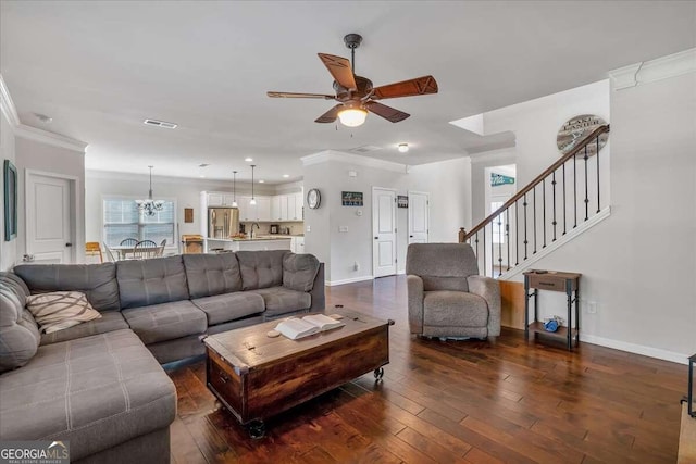 living room with crown molding, dark hardwood / wood-style floors, and ceiling fan with notable chandelier