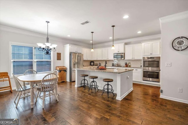 kitchen with a kitchen island with sink, pendant lighting, white cabinetry, appliances with stainless steel finishes, and dark hardwood / wood-style flooring