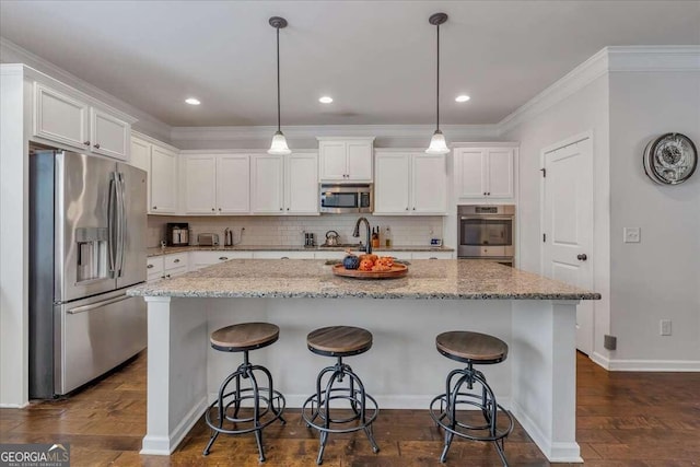 kitchen with dark hardwood / wood-style flooring, stainless steel appliances, pendant lighting, white cabinets, and a center island with sink