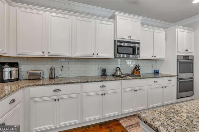 kitchen with ornamental molding, white cabinets, and stainless steel appliances