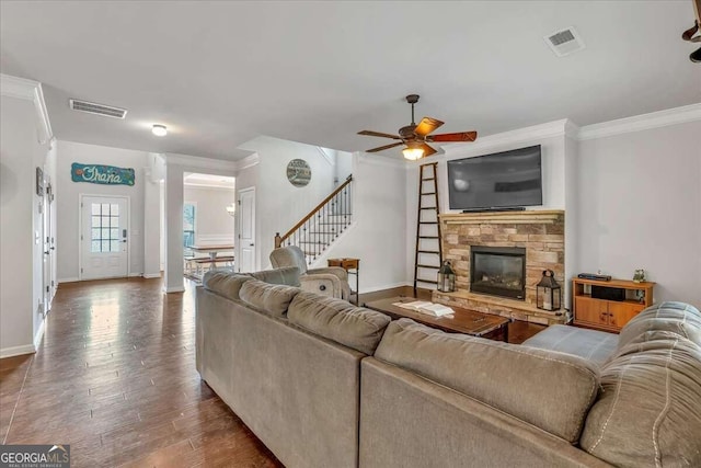 living room with ornamental molding, wood-type flooring, a fireplace, and ceiling fan