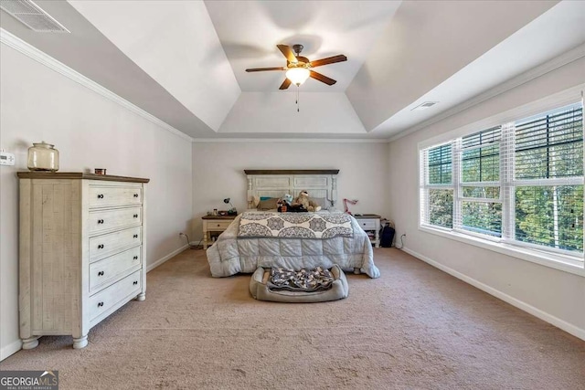 bedroom featuring ornamental molding, light colored carpet, a tray ceiling, and ceiling fan