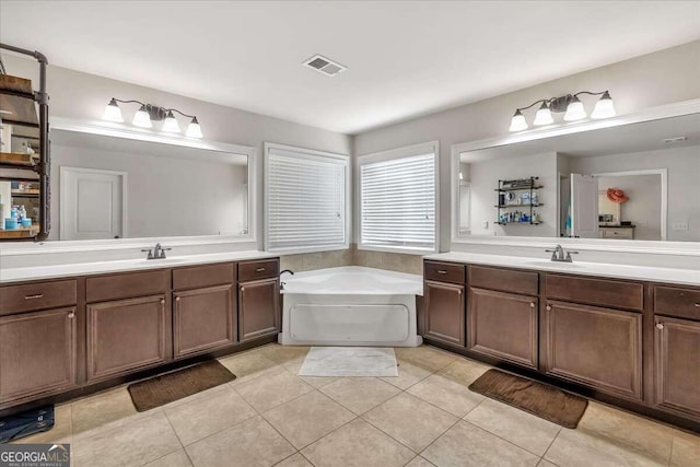 bathroom with a bathing tub, vanity, and tile patterned flooring