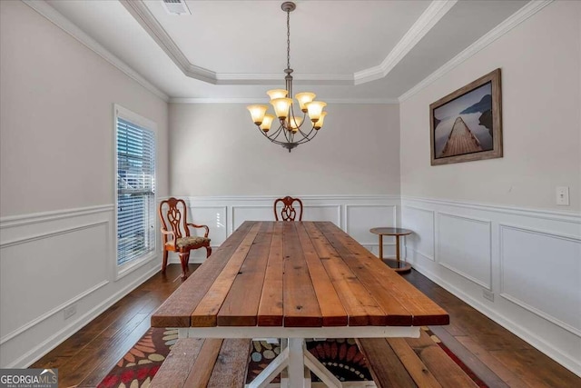 dining area featuring ornamental molding, a notable chandelier, dark hardwood / wood-style floors, and a tray ceiling