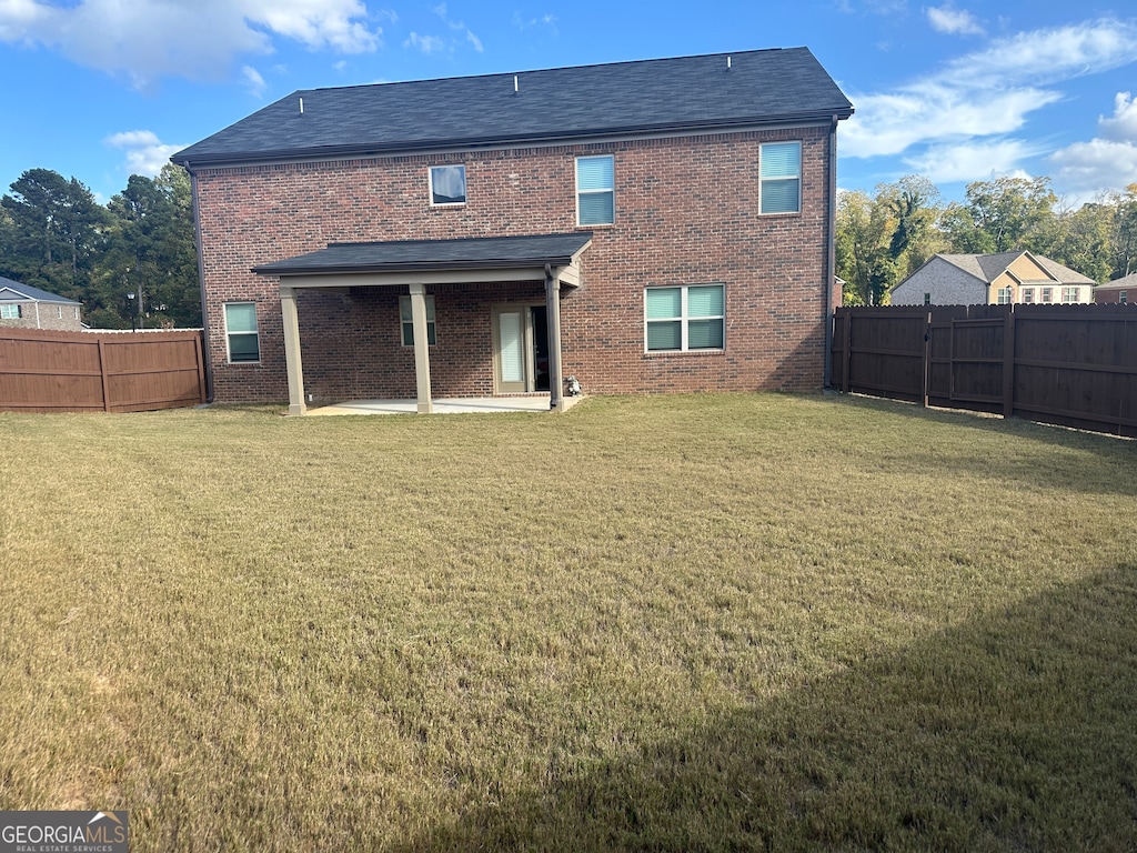 back of property with a patio area and a lawn