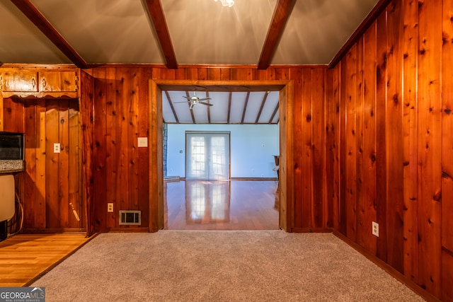 interior space with ceiling fan, vaulted ceiling with beams, hardwood / wood-style flooring, and wood walls