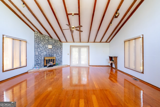 unfurnished living room with beam ceiling, light hardwood / wood-style flooring, a fireplace, high vaulted ceiling, and ceiling fan