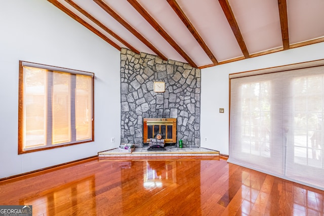 unfurnished living room with a wealth of natural light, beam ceiling, and hardwood / wood-style flooring