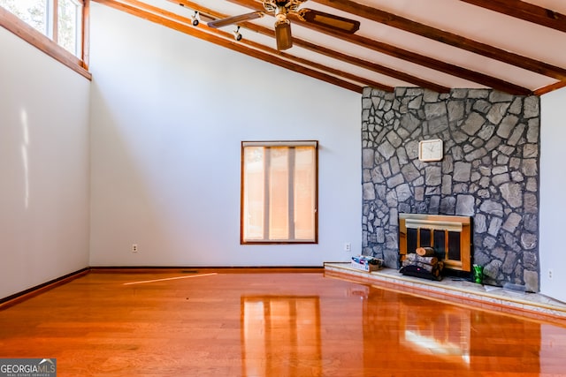 unfurnished living room featuring light hardwood / wood-style floors, beam ceiling, a fireplace, high vaulted ceiling, and ceiling fan