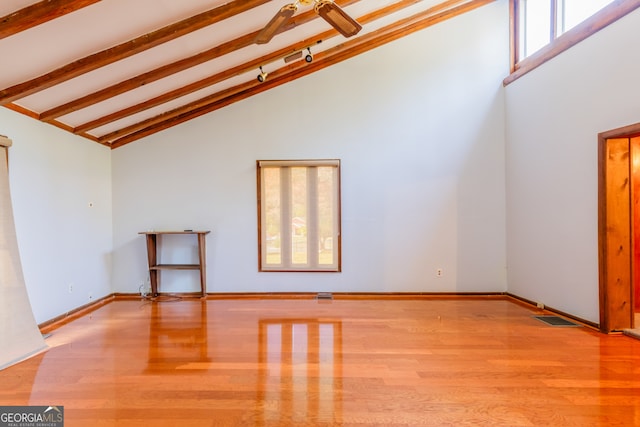 unfurnished living room featuring beam ceiling, light hardwood / wood-style flooring, and high vaulted ceiling