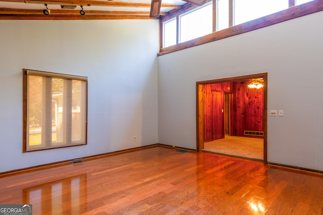 unfurnished living room with hardwood / wood-style flooring, high vaulted ceiling, beamed ceiling, and ceiling fan