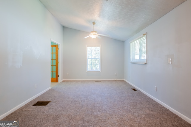 carpeted spare room featuring vaulted ceiling, a textured ceiling, and ceiling fan