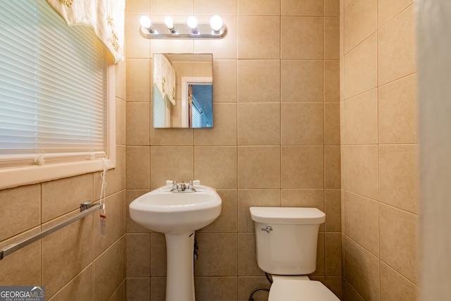 bathroom with tile walls and toilet