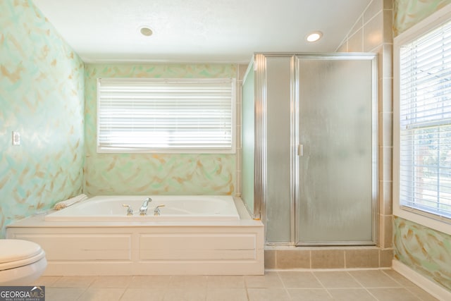 bathroom featuring toilet, a healthy amount of sunlight, and separate shower and tub