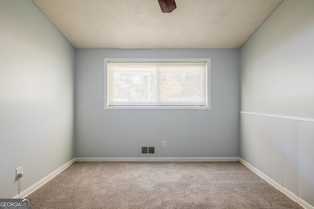 carpeted spare room with a textured ceiling and ceiling fan