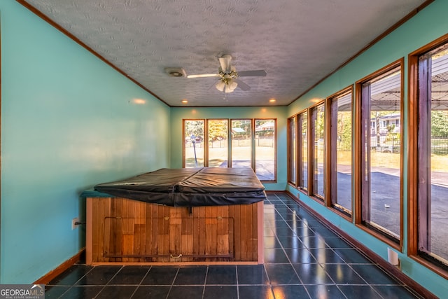 unfurnished sunroom featuring ceiling fan and a jacuzzi