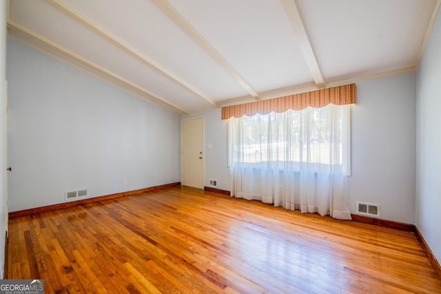 unfurnished room featuring vaulted ceiling with beams and light wood-type flooring