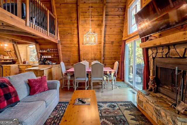 living room featuring hardwood / wood-style floors, a fireplace, a healthy amount of sunlight, and wood walls