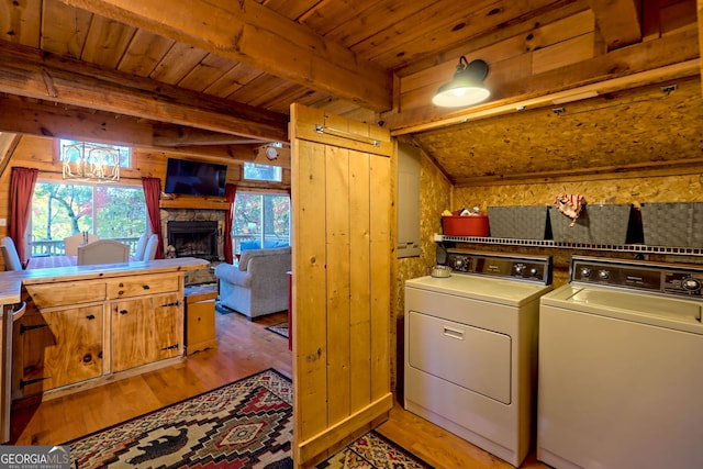 laundry area with washing machine and dryer, a fireplace, light hardwood / wood-style floors, wooden ceiling, and wooden walls