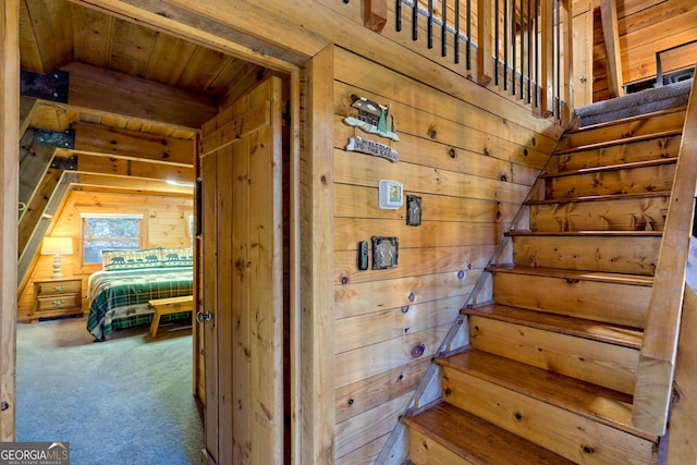 staircase with carpet floors and wooden walls