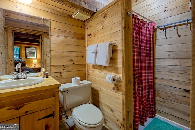 bathroom with toilet, wood walls, and vanity