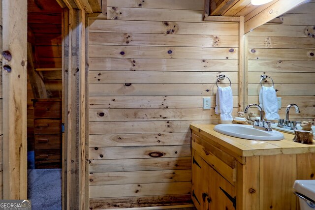 bathroom featuring vanity, toilet, and wooden walls