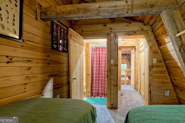 unfurnished bedroom with light carpet, vaulted ceiling with beams, and wood walls