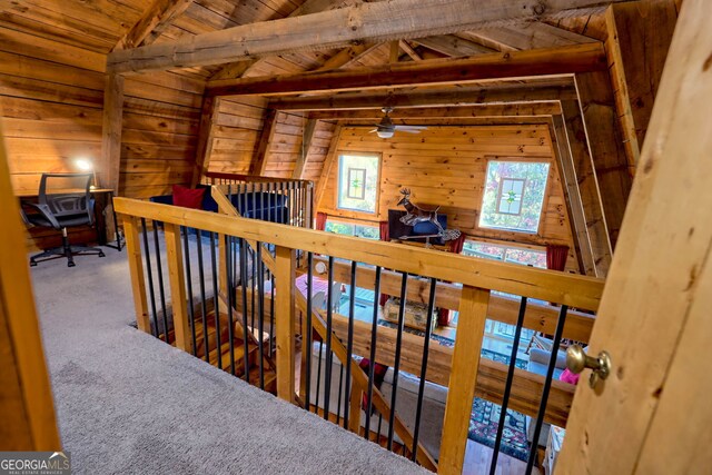 hall featuring wooden walls, vaulted ceiling with beams, carpet floors, and wooden ceiling