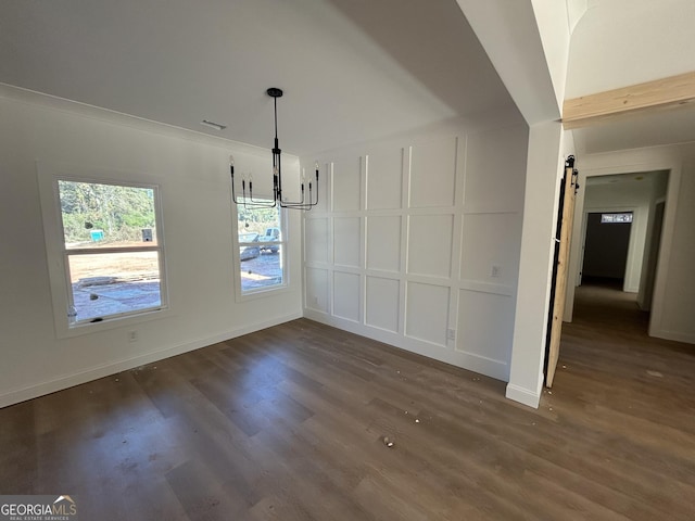 unfurnished dining area featuring an inviting chandelier, dark hardwood / wood-style flooring, and a barn door