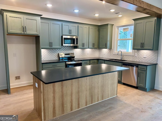 kitchen with sink, green cabinets, stainless steel appliances, a center island, and light wood-type flooring