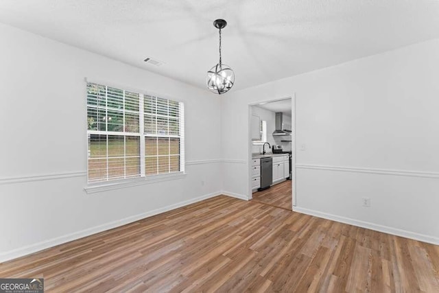 unfurnished dining area featuring light hardwood / wood-style floors and a notable chandelier