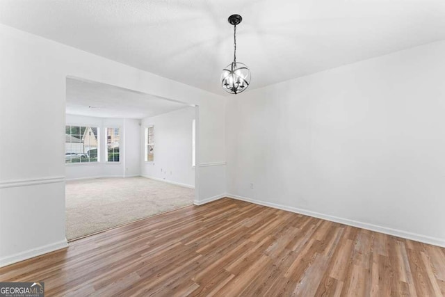 unfurnished dining area with a notable chandelier and wood-type flooring